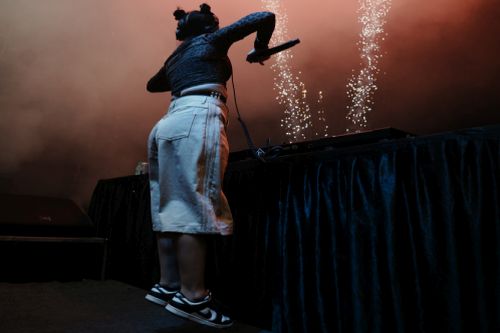 A person on stage with purple lights

AI-generated content may be incorrect.